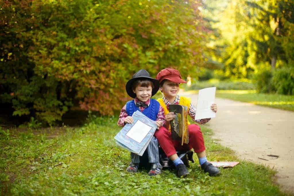 create a summer book club for kids two boys reading books in the sun.